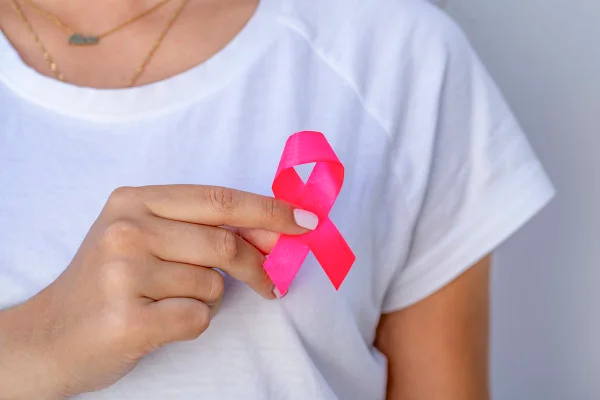 Mulher segurando um laço cor de rosa - Metrópoles
