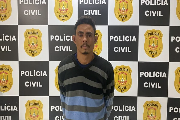 homem pardo com casaco listrado em frente ao painel da PCDF
