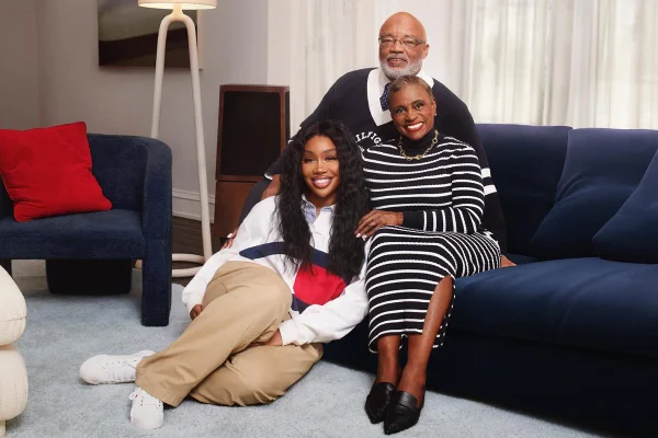 SZA e família em campanha de moda. A cantora está sentada no chão, à frente dos pais, que estão em um sofá - Metrópoles