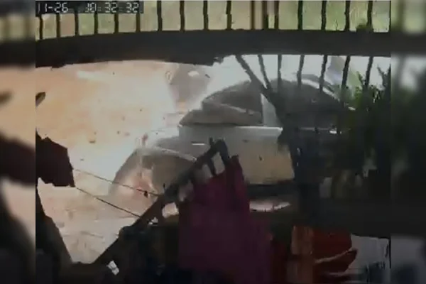 Imagem colorida de carro e portão sendo atingidos por pedra