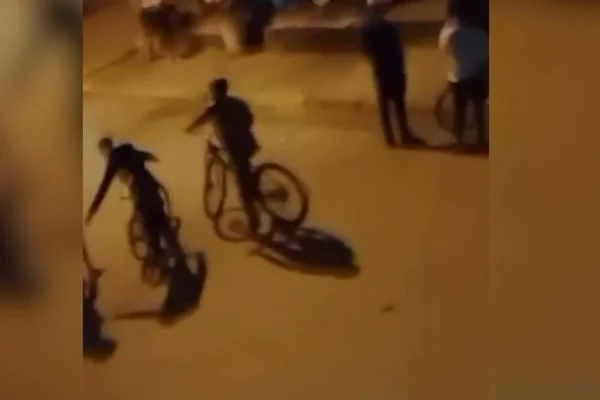 imagem colorida mostra crianças andando de bicicleta em rua à noite. Imagens foram gravadas por uma menina - Metrópoles