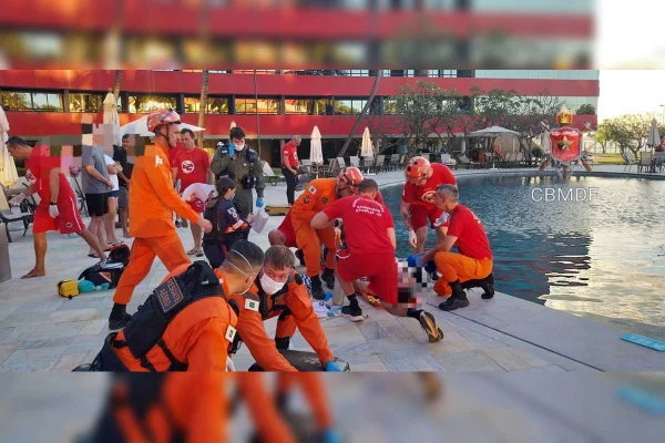 Foto colorida de homem perto de piscina sendo reanimado