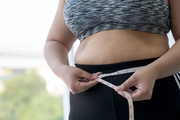 Mulher medindo barriga com fita métrica