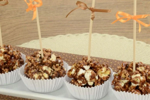 Pipoca no palito com chocolate para deixar a decoração da festa junina mais gostosa