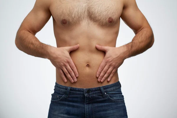 Imagem colorida mostra homem magro sem camisa com as mãos ao redor do umbigo - Metrópoles