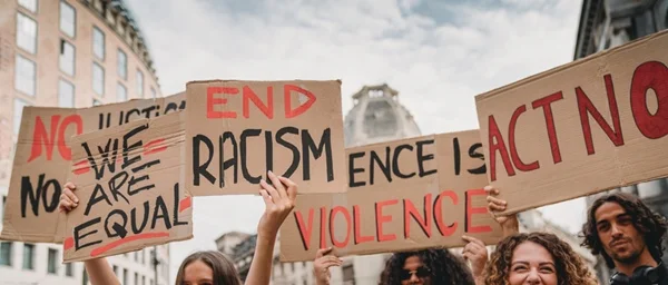 Pessoas segurando cartaz com palavras chega de racismo em inglês