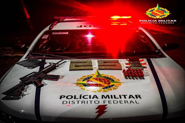 Foto colorida de fuzil e munições em cima de capo de carro de polícia