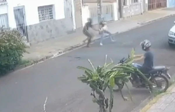 Imagem colorida mostra bandido roubando celular de mulher com um bebê no colo enquanto comparsa o espera em cima de uma moto - Metrópoles