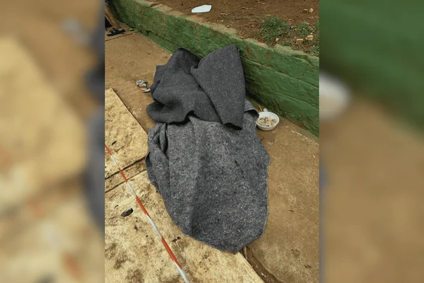 Imagem colorida de um homem em situação de rua coberto com um cobertor acinzentado - Metrópoles