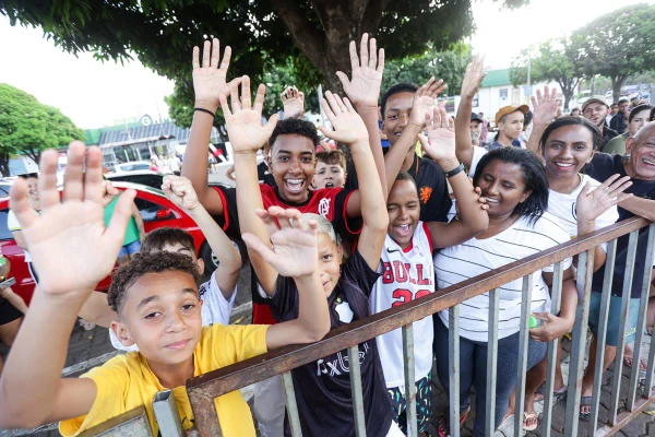 foto colorida de pessoas encostadas em grade - metrópoles