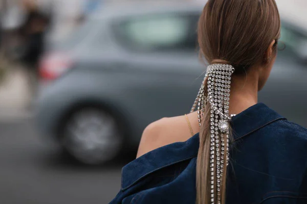 Mulher de costas como o cabelo preso. O penteado é adornado com franjas de strass