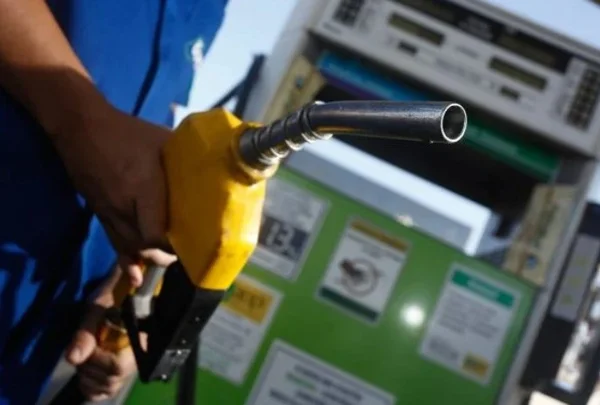 Frentista segurando mangueira de bomba de gasolina- Metrópoles