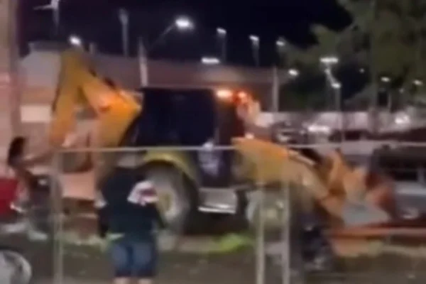 Imagem colorida de escavadeira em trânsito usada por homem para passar por cima de carros - Metrópoles