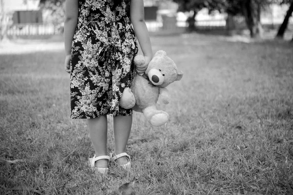 Foto em preto e branco de mina segurando um urso - Metrópoles
