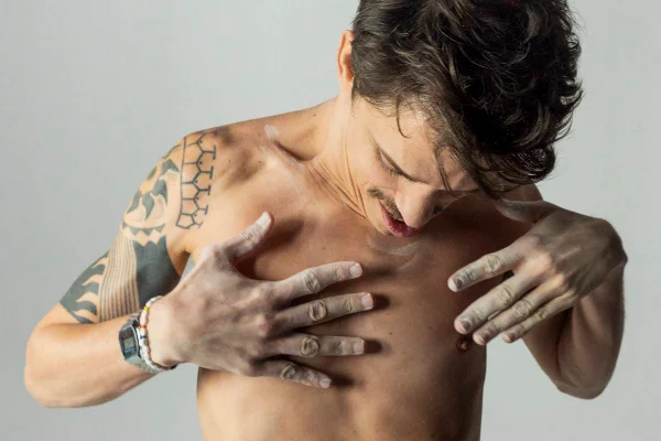 Foto colorida de um homem sem camisa olhando para baixo - Metrópoles