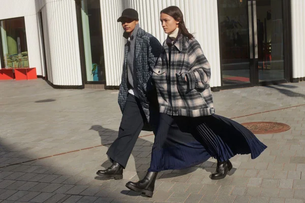 Dois modelos caminham usando looks de frio com tons sóbrios de azul, preto e cinza - Metrópoles
