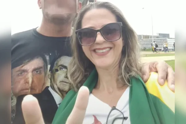 mulher com bandeira do Brasil nos ombros ao lado de homem com camiseta com o rosto do ex-presidente Jair Bolsonaro