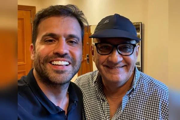 Fotografia colorida de dois homens sorrindo para foto lado a lado