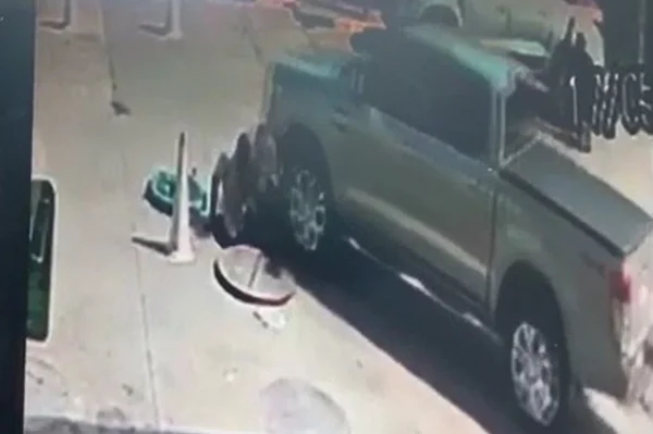 Caminhonete atropelando homem no chão ao lado de cone