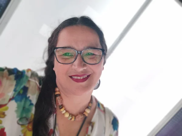 imagem colorida mostra mulher sorrindo. ela usa óculos e batom rosa escuro, é branca e tem o cabelo preso. metrópoles