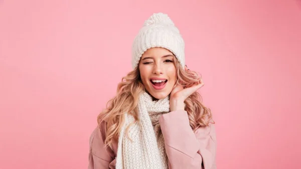 Mulher com roupa de frio piscando e sorrindo para a câmera