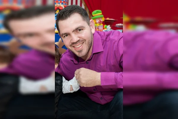 homem de camisa rosa posando para foto
