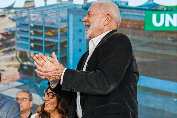 Imagem colorida de homem branco com cabelos brancos vestindo blazer preto e camisa branca; ele está de lado e aplaude com as mãos - Metrópoles