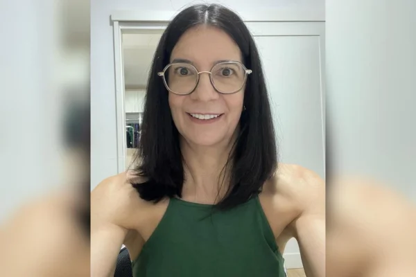 Foto colorida de mulher usando óculos sorrindo para câmera - Metrópoles