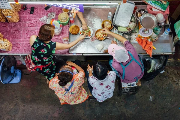 Foto colorida de várias pessoas comendo - Metrópoles