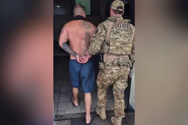 Imagens coloridas mostram homem de costas, sem camisa, tatuagem no ombro direito, bermuda azul, sendo conduzido por policial com farda camuflada