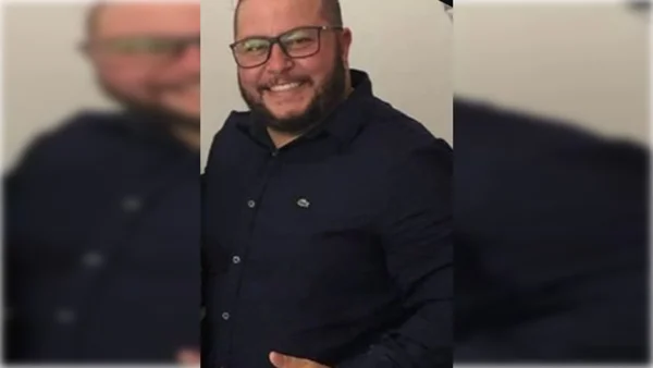 Homem de óculos e camisa azul sorrindo - Metrópoles