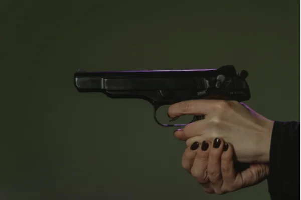 Imagem colorida, mulher segurando um revólver