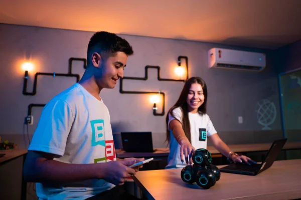 Fotografia colorida mostrando dois alunos, um homem e uma mulher, mexendo em equipamentos tecnológicos em uma mesa-Metrópoles