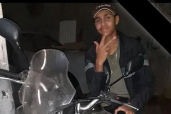 Jovem pardo dá sinal com mão sentado em moto - Metrópoles