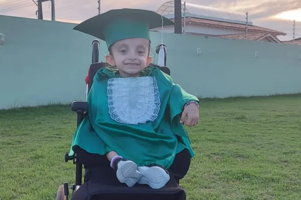 Imagem colorida: menina de 6 anos com beca de formatura ABC - Metrópoles