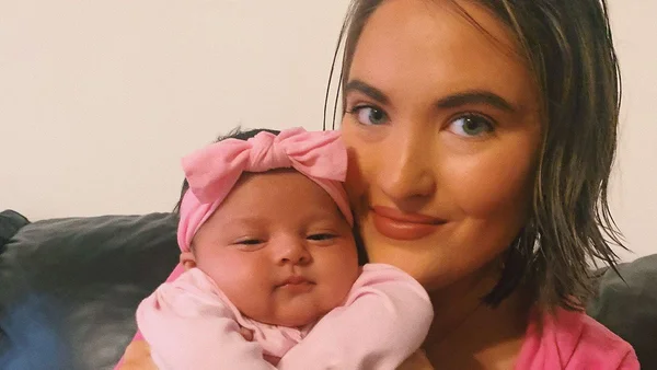 Mulher branca de olho azul segurando uma bebê branca de olho azul próximo ao seu rosto