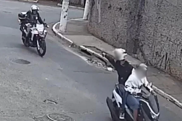 Reprodução colorida com garupa de moto, em movimento, apontando arma para PM durante fuga - Metrópoles