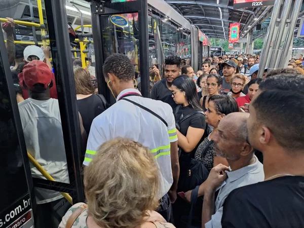 Imagem colorida mostra muitas pessoas tentando entrar em ônibus na frente da estação Pinheiros - Metrópoles