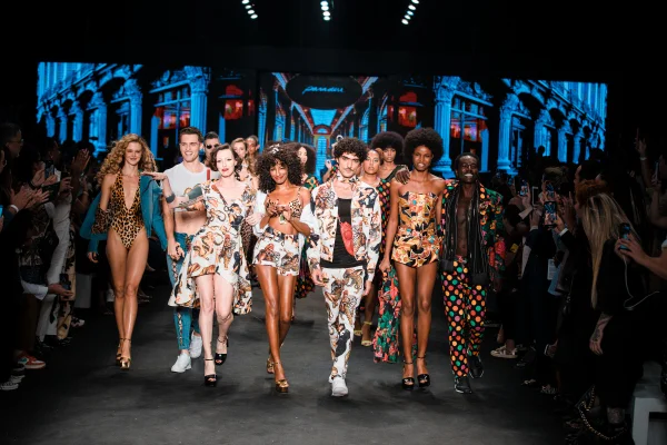 A imagem mostra diversos modelos lado a lado andando em passarela no São Paulo Fashion Week