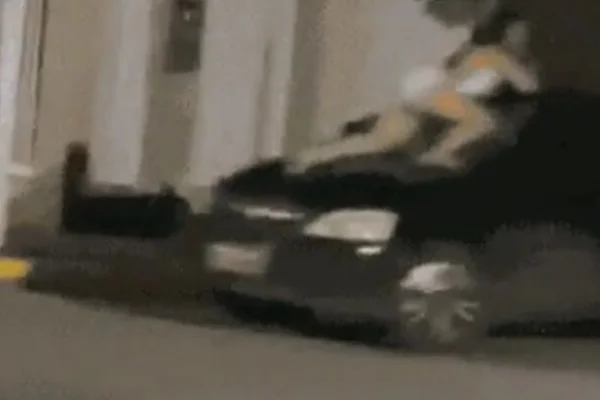 Mulher agarrada a carro em movimento