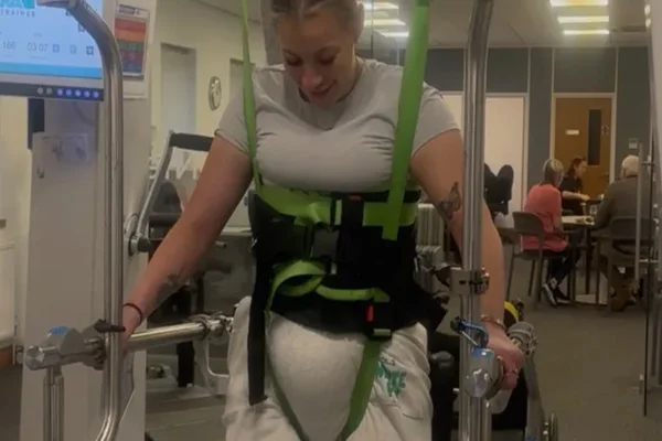 Mulher em pé utilizando equipamento para paralisia