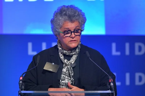 Fotografia colorida de mulher discursando em púlpito