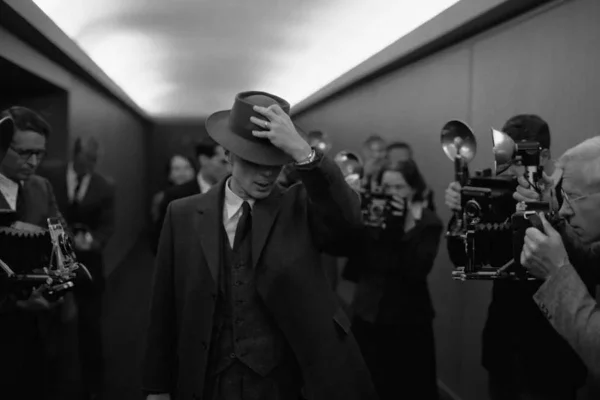 Na foto preto e branco, homem anda em corredor enquanto pessoas fotografam ele - Metrópoles