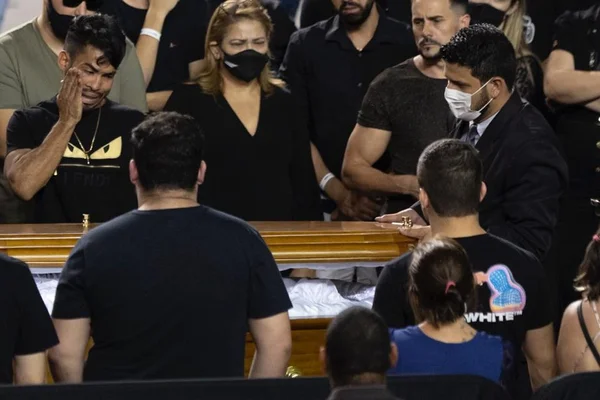 Pessoas de preto em volta de caixão