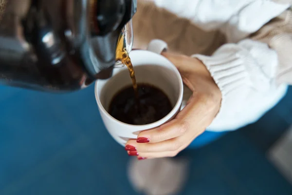 Close de uma mulher servindo café quente filtrado em uma caneca enquanto fica em casa. Metrópoles - bebida é aliada para combater gordura no fígado