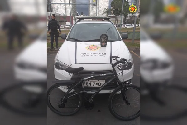 Bicicleta em frente a viatura da PMDF e policial ao lado