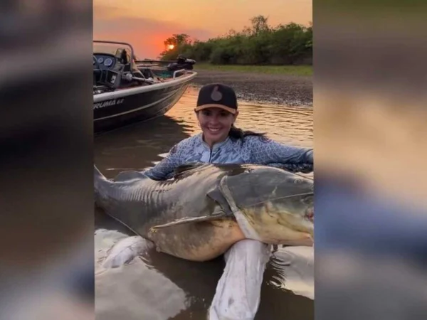 Foto colorida da pescadora Sabrynne Mariot segurado peixe Jaú - Metrópoles