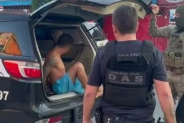 Imagem colorida de homem preso dentro de viatura policial. Metrópoles