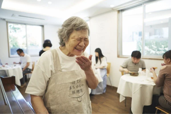 Idosa japonesa sorrindo no Restaurante dos Pedidos Errados