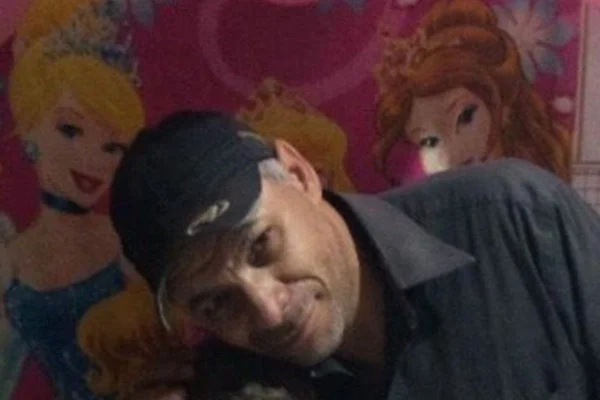 Foto colorida de homem de bone posando para foto em aniversário de criança